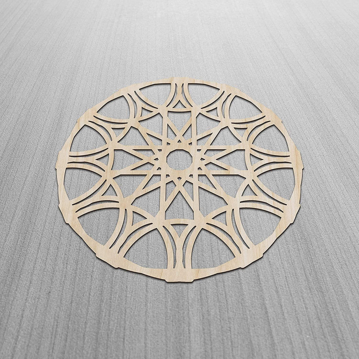 Birch plywood mandala wall panel with whirl-pattern lattice cut-work, shown on a grey textured surface